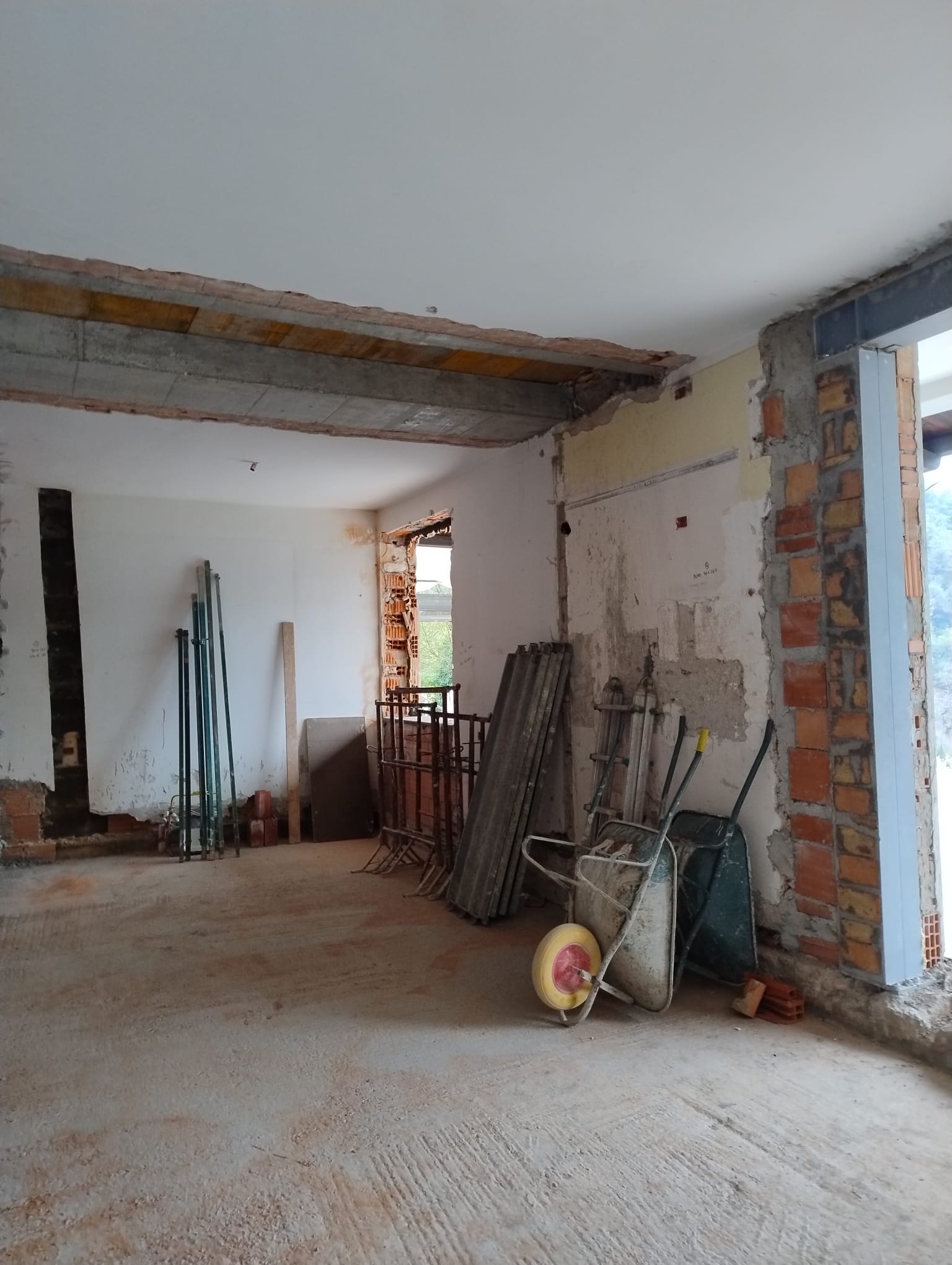 Cantiere di ristrutturazione con apertura in un muro portante: trave in cemento armato, cerchiatura metallica e puntelli di sostegno provvisori