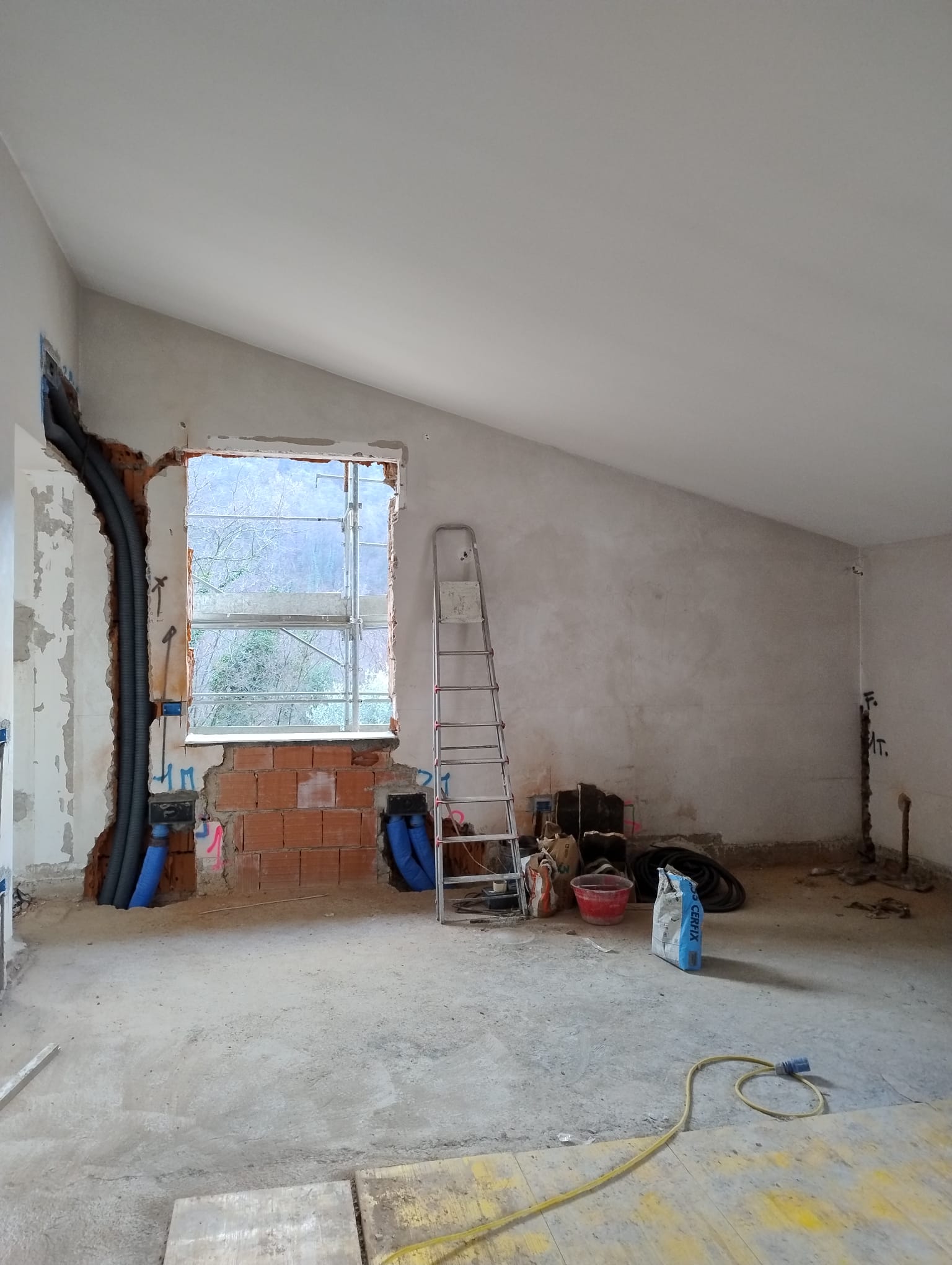 Interno di un cantiere di ristrutturazione a Brescia con corrugati degli impianti a vista, vano finestra modificato e ponteggio esterno