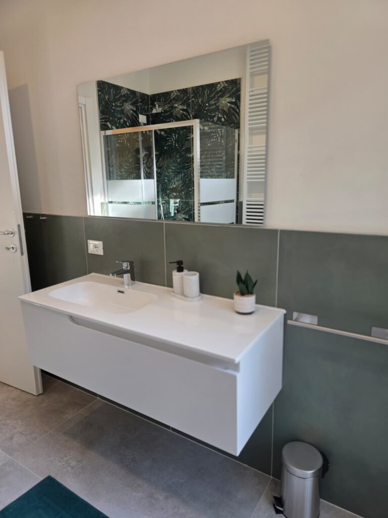 Bagno privato con lavabo sospeso e rivestimento verde nello studentato