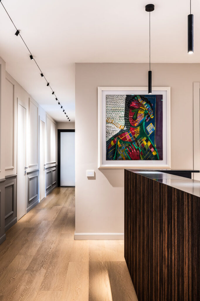 Corridoio di ingresso con boiserie continua che ingloba le porte nel disegno della parete