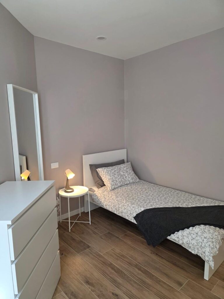 Camera singola dello studentato con arredo IKEA e parete grigio caldo