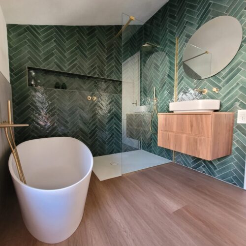 Bagno con vasca freestanding e piastrelle verde smeraldo a spina di pesce, ristrutturazione di un appartamento a Brescia