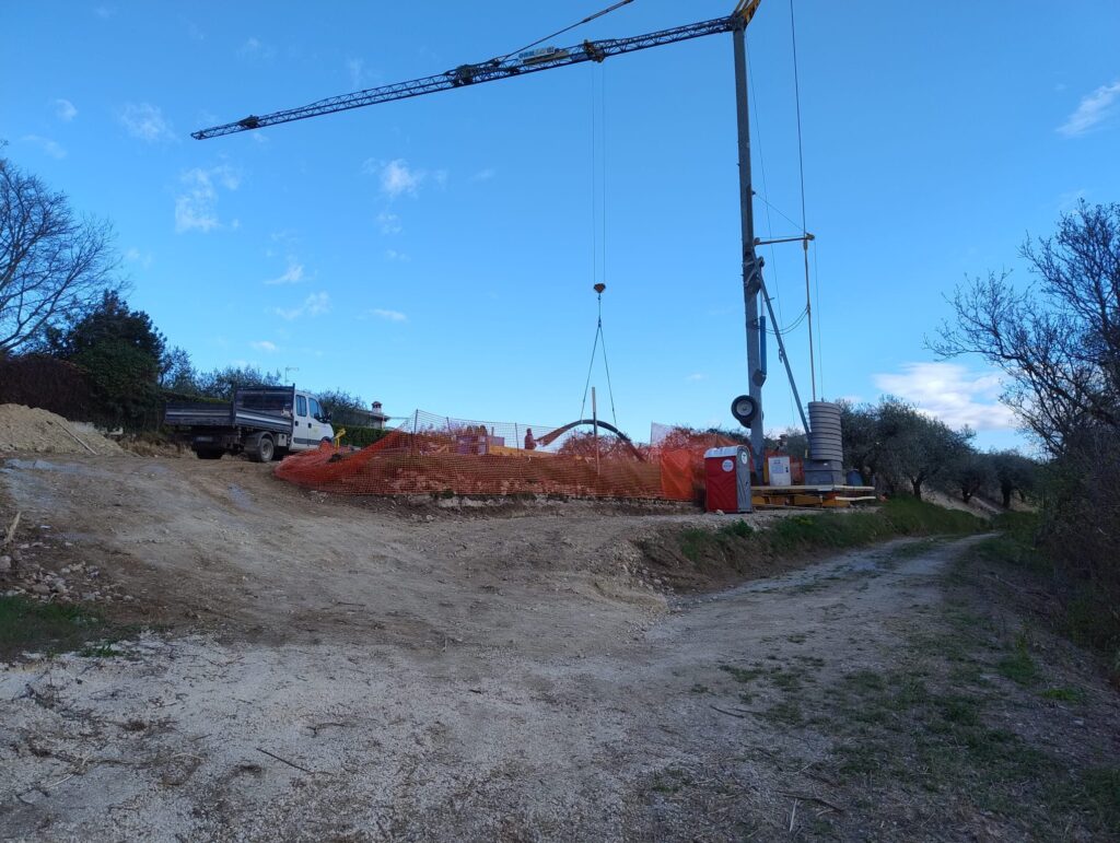 Fase di scavo e allestimento del cantiere con gru a torre sul lotto in pendenza