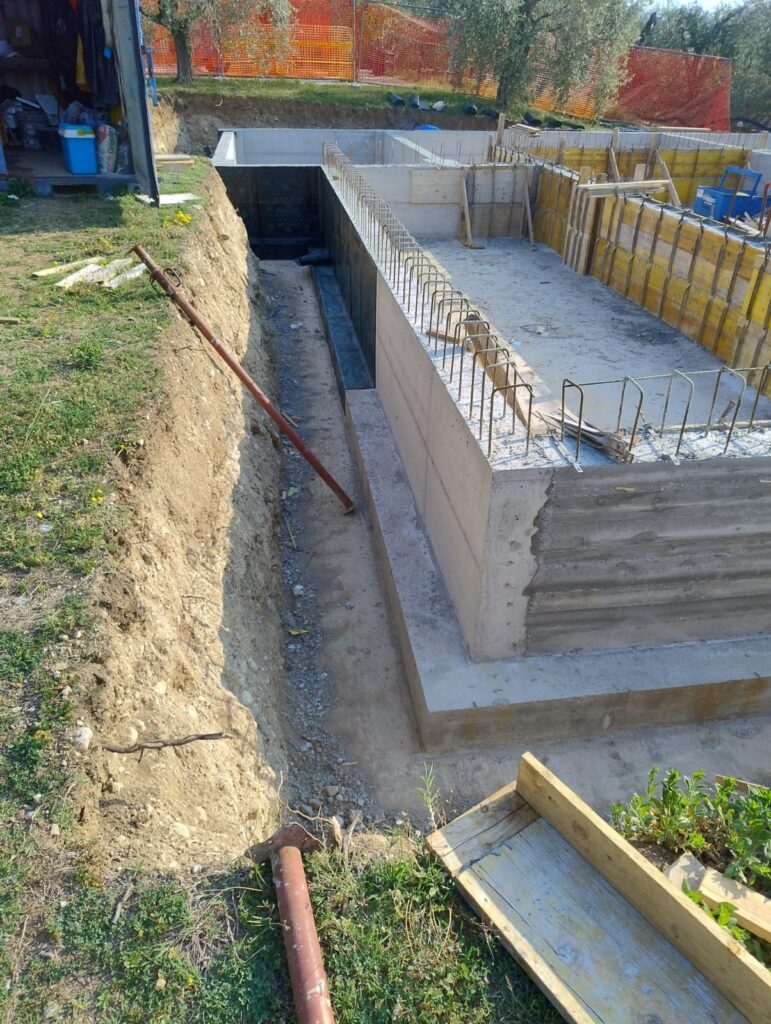 Vasca della piscina in calcestruzzo armato con locale tecnico interrato adiacente e casseri di getto